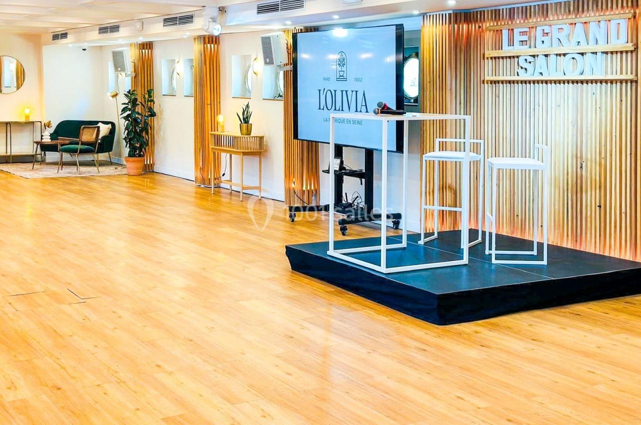 Salle lumineuse avec parquet, estrade équipée de deux chaises hautes et écran, décorée de bois et miroirs.