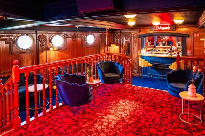 Entrée d'un restaurant aménagé sur un bateau, avec une passerelle en bois et des plantes en pot.