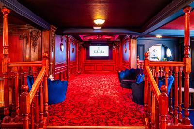 Entrée d'un restaurant aménagé sur un bateau, avec une passerelle en bois et des plantes en pot.