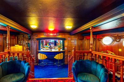 Entrée d'un restaurant aménagé sur un bateau, avec une passerelle en bois et des plantes en pot.