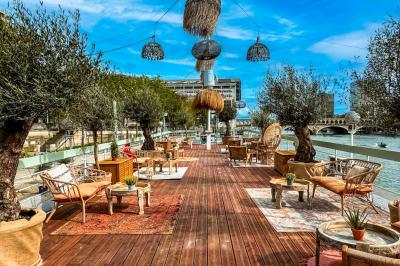 Entrée d'un restaurant aménagé sur un bateau, avec une passerelle en bois et des plantes en pot.
