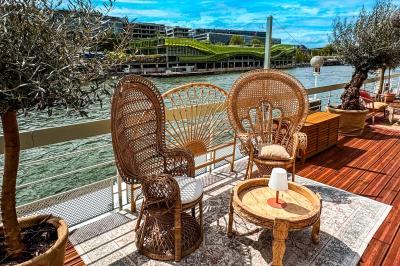 Entrée d'un restaurant aménagé sur un bateau, avec une passerelle en bois et des plantes en pot.