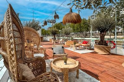 Entrée d'un restaurant aménagé sur un bateau, avec une passerelle en bois et des plantes en pot.