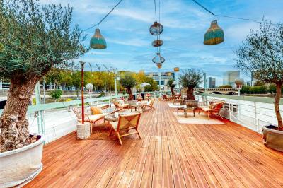 Entrée d'un restaurant aménagé sur un bateau, avec une passerelle en bois et des plantes en pot.