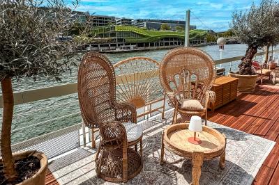 Entrée d'un restaurant aménagé sur un bateau, avec une passerelle en bois et des plantes en pot.