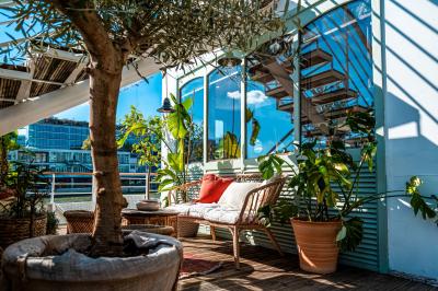 Entrée d'un restaurant aménagé sur un bateau, avec une passerelle en bois et des plantes en pot.