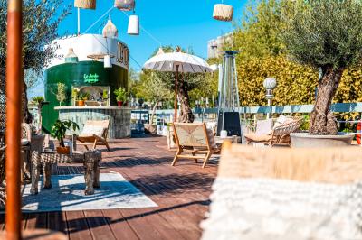 Entrée d'un restaurant aménagé sur un bateau, avec une passerelle en bois et des plantes en pot.