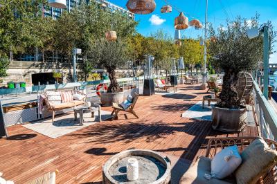 Entrée d'un restaurant aménagé sur un bateau, avec une passerelle en bois et des plantes en pot.