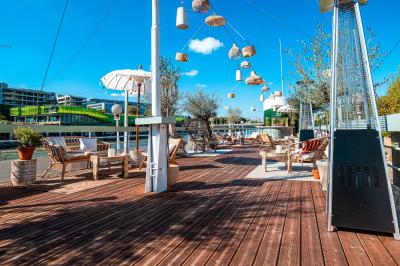 Entrée d'un restaurant aménagé sur un bateau, avec une passerelle en bois et des plantes en pot.