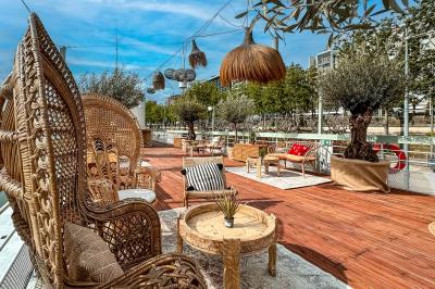 Entrée d'un restaurant aménagé sur un bateau, avec une passerelle en bois et des plantes en pot.