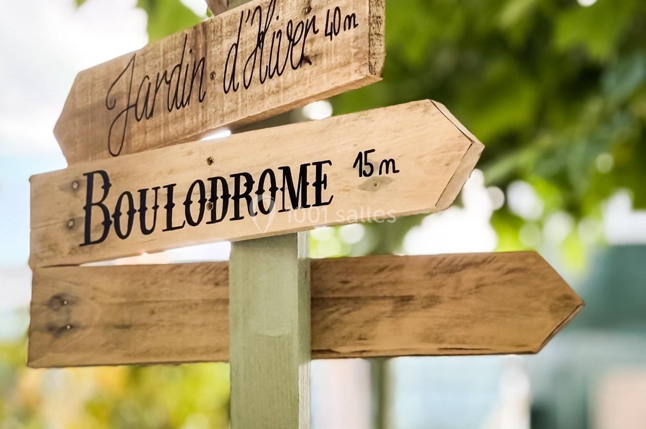 Panneau en bois indiquant les directions pour un jardin d'hiver à 40 m et un boulodrome à 15 m.