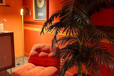 Miniature Location salle Paris 12 (Paris) - L'Olivia #118 Platine vinyle sur un meuble en bois, plante en pot et lampes dans une pièce aux tons rouges et orange.