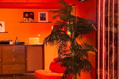 Miniature Location salle Paris 12 (Paris) - L'Olivia #127 Platine vinyle sur un meuble en bois, plante en pot et lampes dans une pièce aux tons rouges et orange.