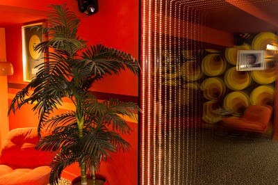 Miniature Location salle Paris 12 (Paris) - L'Olivia #128 Platine vinyle sur un meuble en bois, plante en pot et lampes dans une pièce aux tons rouges et orange.