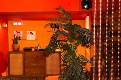 Miniature Location salle Paris 12 (Paris) - L'Olivia #129 Platine vinyle sur un meuble en bois, plante en pot et lampes dans une pièce aux tons rouges et orange.