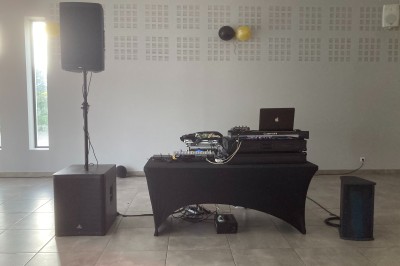 Équipement de DJ comprenant une table de mixage, des platines, un contrôleur et divers câbles sur une table.