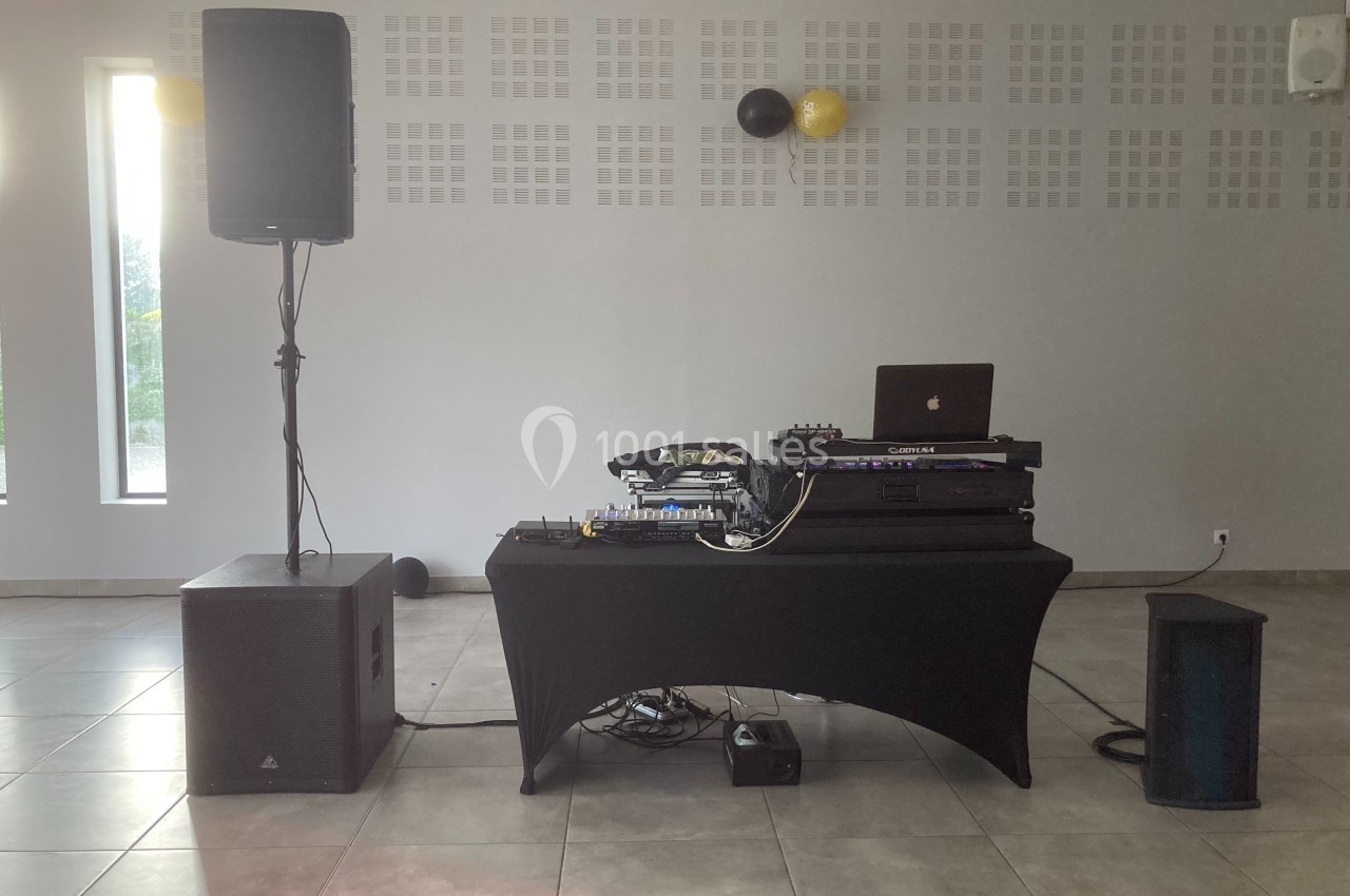Matériel de sonorisation avec table de mixage, ordinateur et enceintes installé dans une salle lumineuse.