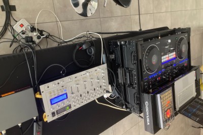 Équipement de DJ comprenant une table de mixage, des platines, un contrôleur et divers câbles sur une table.
