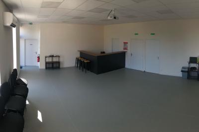 Salle lumineuse avec un comptoir en bois, quatre tabourets hauts, trois portes blanches et un coin avec ordinateur et…