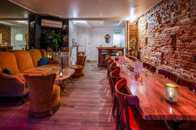 Intérieur d'un bar avec comptoir bleu éclairé, tabourets hauts, tables en bois et murs en briques apparentes.