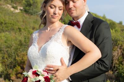 Un couple s'embrasse tendrement dans un cadre naturel entouré de branches d'olivier.