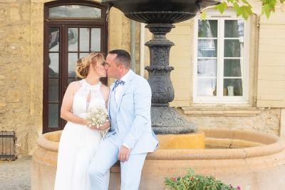 Un couple s'embrasse tendrement dans un cadre naturel entouré de branches d'olivier.