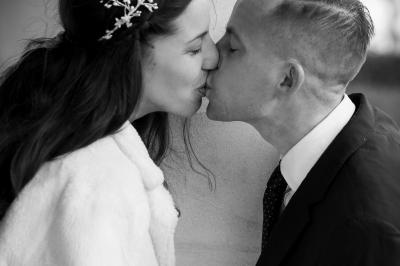 Un couple s'embrasse tendrement dans un cadre naturel entouré de branches d'olivier.