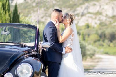 Un couple s'embrasse tendrement dans un cadre naturel entouré de branches d'olivier.
