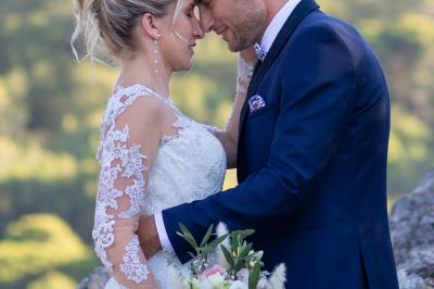 Un couple s'embrasse tendrement dans un cadre naturel entouré de branches d'olivier.