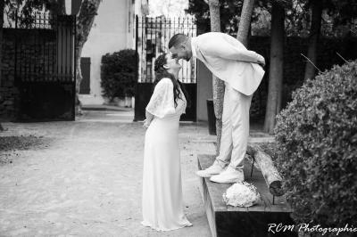 Un couple s'embrasse tendrement dans un cadre naturel entouré de branches d'olivier.