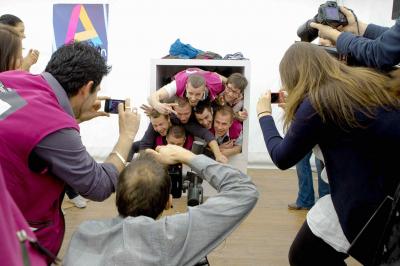 Femme portant des lunettes et un blazer à carreaux, posant devant un fond clair.