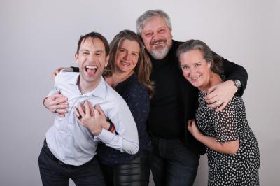 Femme portant des lunettes et un blazer à carreaux, posant devant un fond clair.