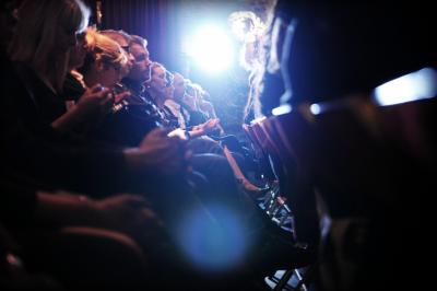 Femme portant des lunettes et un blazer à carreaux, posant devant un fond clair.