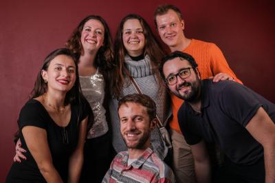 Femme portant des lunettes et un blazer à carreaux, posant devant un fond clair.