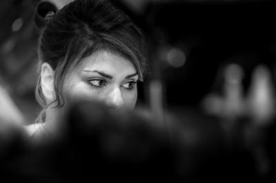 Femme souriante portant un blazer imprimé coloré, un t-shirt gris et un jean, posant devant un fond blanc.