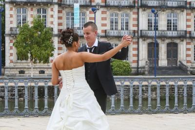 Femme souriante portant un blazer imprimé coloré, un t-shirt gris et un jean, posant devant un fond blanc.