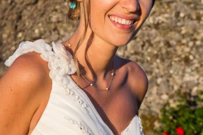 Femme souriante portant un blazer imprimé coloré, un t-shirt gris et un jean, posant devant un fond blanc.