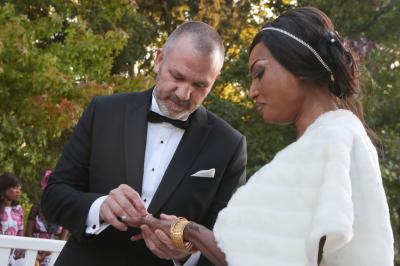 Femme souriante portant un blazer imprimé coloré, un t-shirt gris et un jean, posant devant un fond blanc.