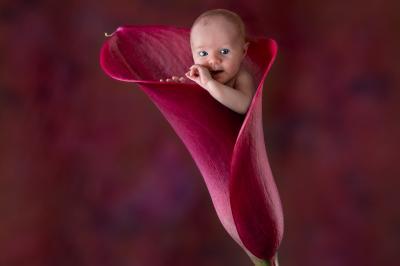 Femme souriante portant un blazer imprimé coloré, un t-shirt gris et un jean, posant devant un fond blanc.