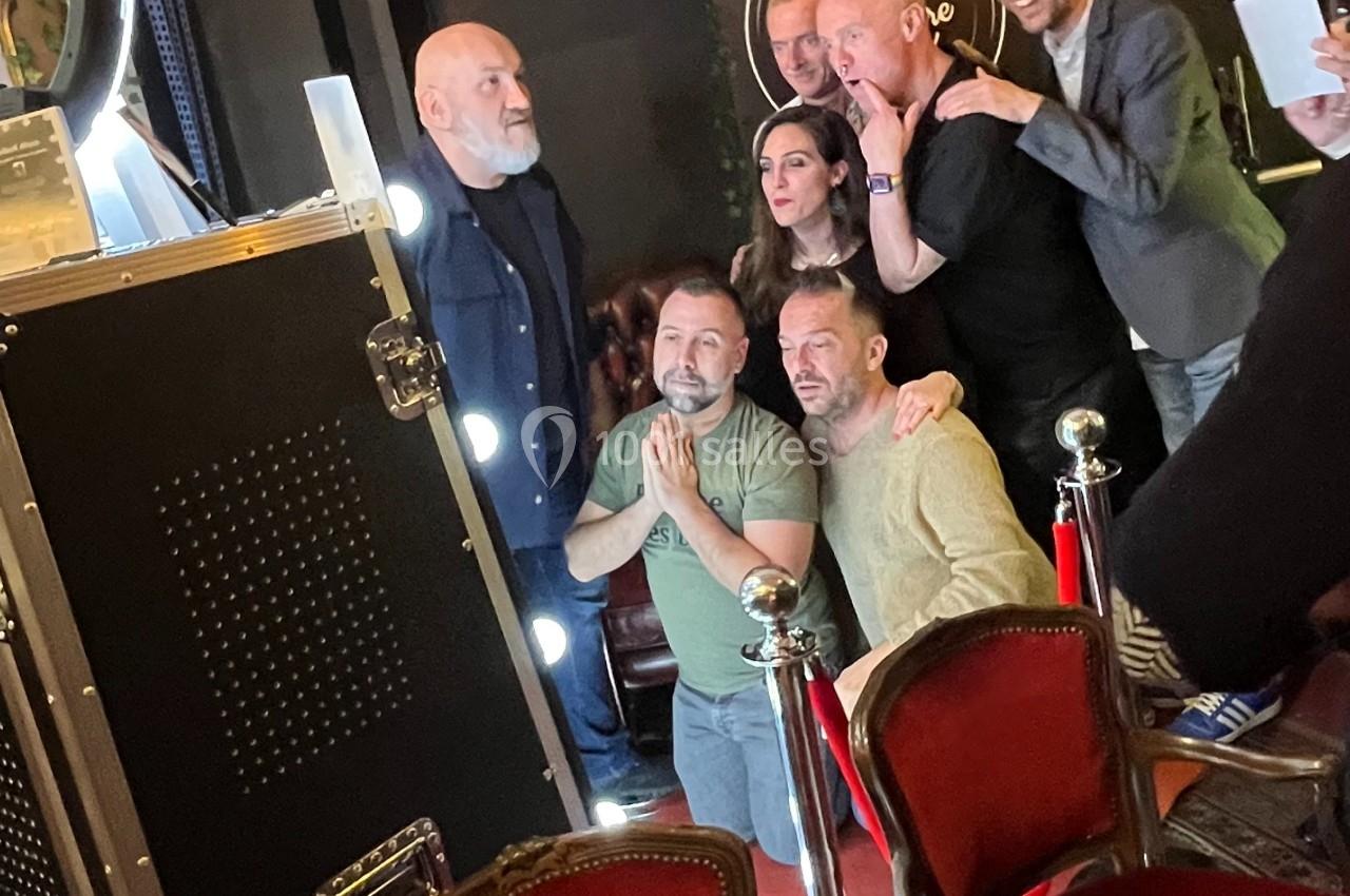Des personnes posent ensemble devant un photobooth dans un espace intérieur avec des chaises rouges au premier plan.