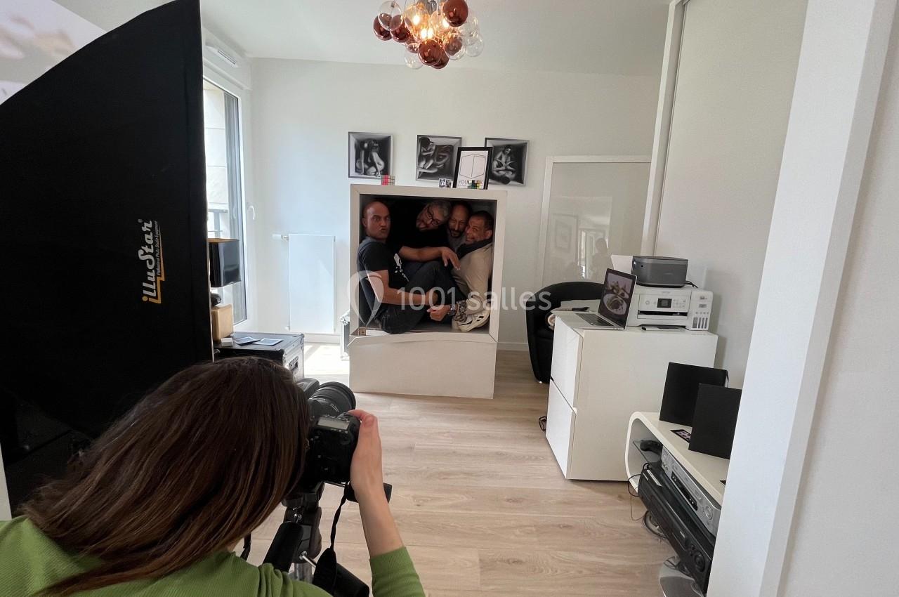 Une photographe capture trois personnes assises ensemble dans une étagère blanche dans un studio lumineux.