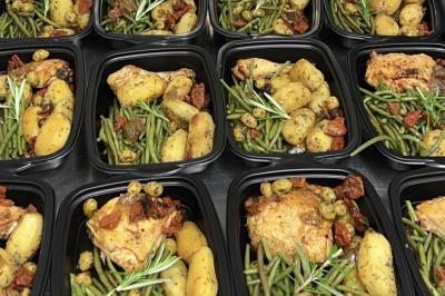 Pizza garnie de jambon cru, olives noires, artichauts, tomates séchées, fromage râpé et filet de pesto.