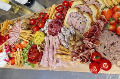 Pizza garnie de jambon cru, olives noires, artichauts, tomates séchées, fromage râpé et filet de pesto.