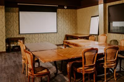 Salon vintage avec canapé, fauteuils, table basse en bois, tapis oriental, lampes et miroirs sur un mur à motifs.