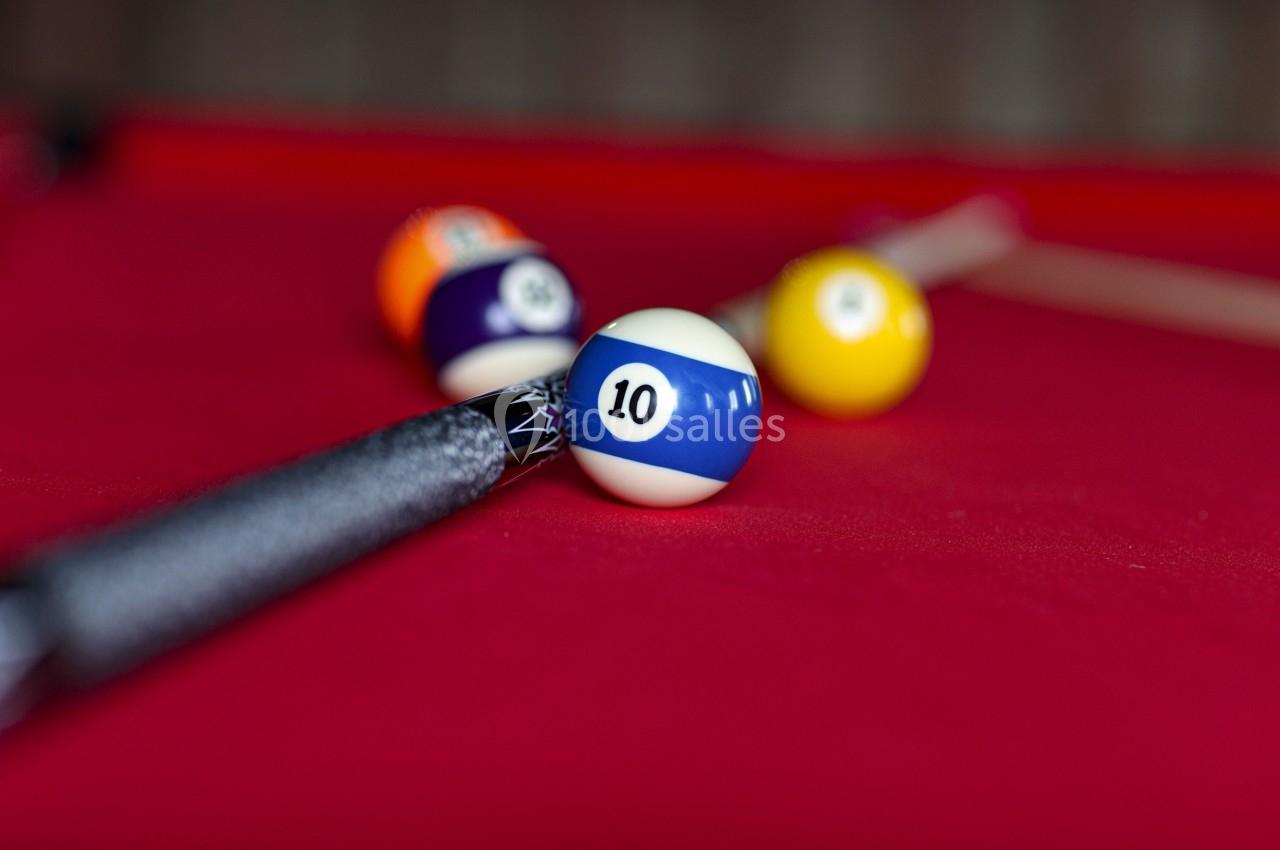 Bille de billard numéro 10 sur une table rouge, avec une queue de billard en arrière-plan.