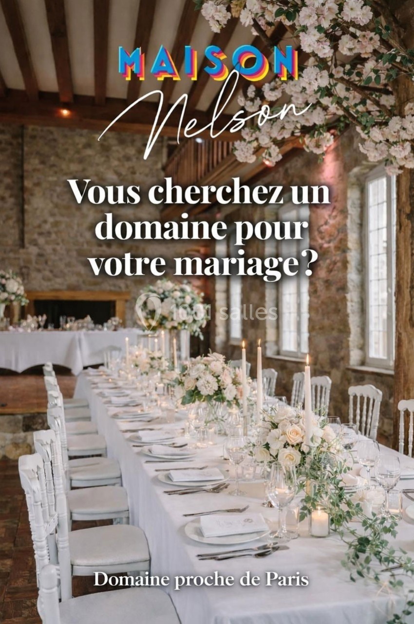 Salle de réception élégante avec longues tables décorées de fleurs blanches, chandeliers et murs en pierre apparente.