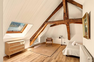 Miniature Location salle Villecerf (Seine-et-Marne) - Maison Nelson #32 Chambre lumineuse avec lit double, parquet en bois, commode, fenêtres et puits de lumière donnant sur un extérieur verdoyant.