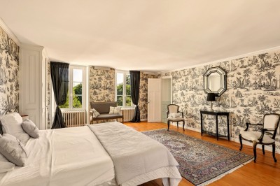 Miniature Location salle Villecerf (Seine-et-Marne) - Maison Nelson #33 Chambre lumineuse avec lit double, parquet en bois, commode, fenêtres et puits de lumière donnant sur un extérieur verdoyant.