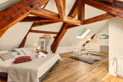 Miniature Location salle Villecerf (Seine-et-Marne) - Maison Nelson #37 Chambre lumineuse avec lit double, parquet en bois, commode, fenêtres et puits de lumière donnant sur un extérieur verdoyant.