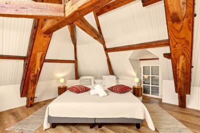 Miniature Location salle Villecerf (Seine-et-Marne) - Maison Nelson #38 Chambre lumineuse avec lit double, parquet en bois, commode, fenêtres et puits de lumière donnant sur un extérieur verdoyant.